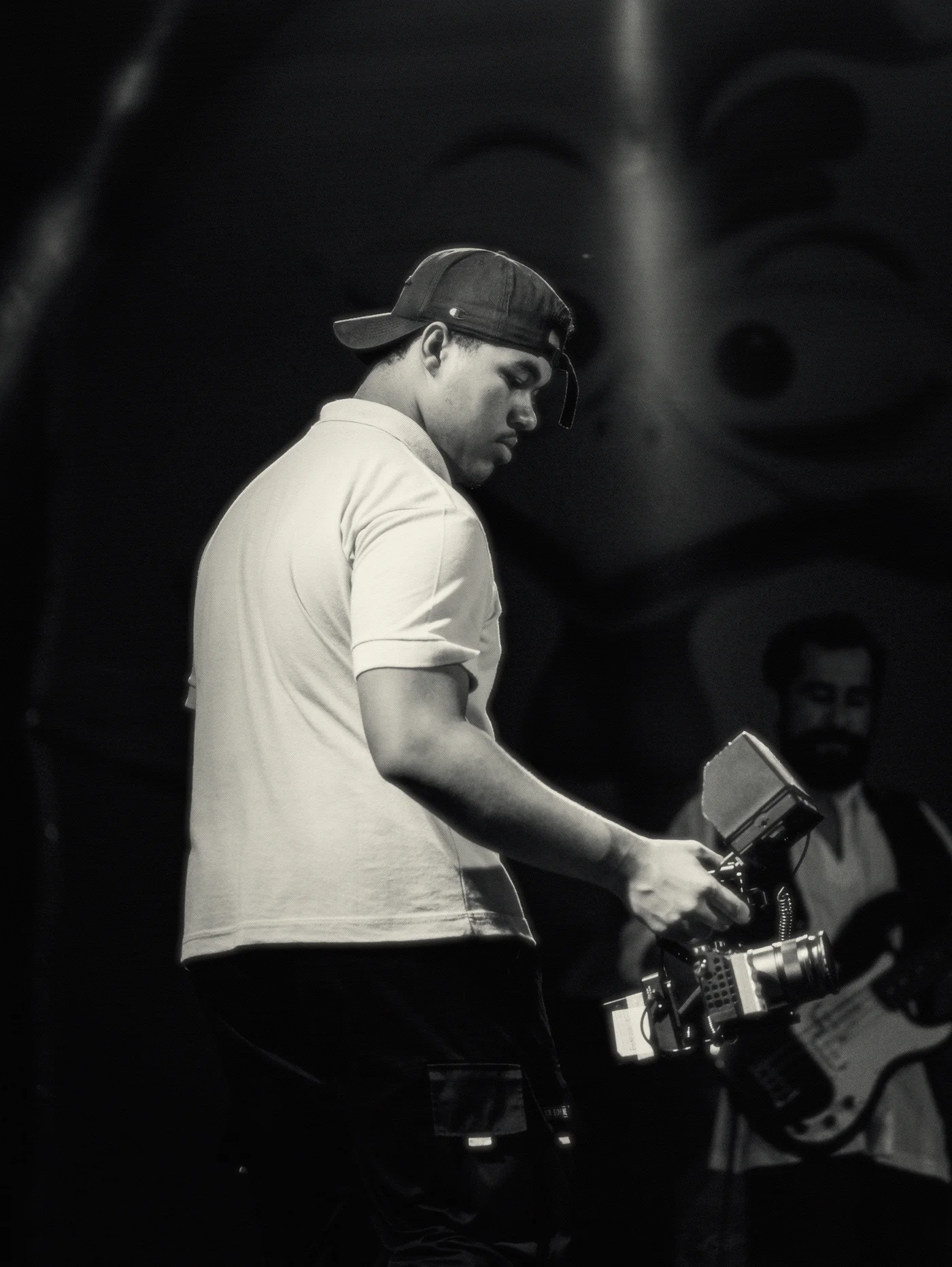 Isaac de boné, em cima do palco, segurando a câmera no estabilizador